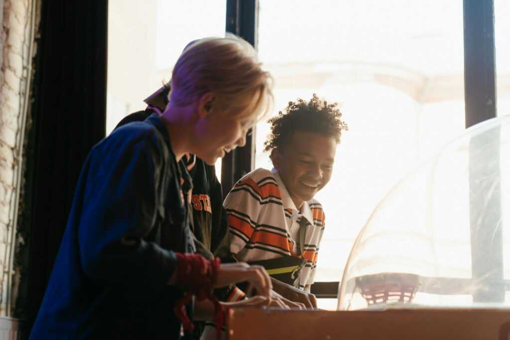 Teenagers having fun while playing games at an indoor arcade, showcasing youthful joy and friendship.